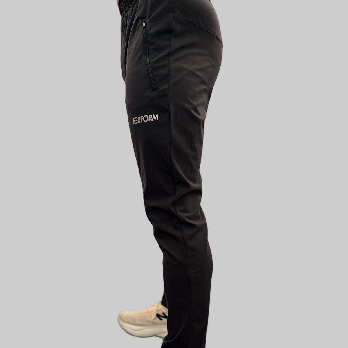 Side view of black Off Duty Casual Pant for men with zip pocket and subtle performance details, worn with white sneakers