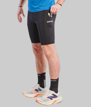 Man wearing black TechBoost Korte Tight shorts for running, paired with black socks and white running shoes.