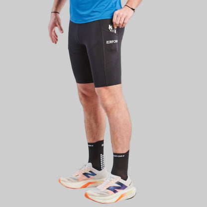 Man wearing black TechBoost Korte Tight shorts for running, paired with black socks and white running shoes.